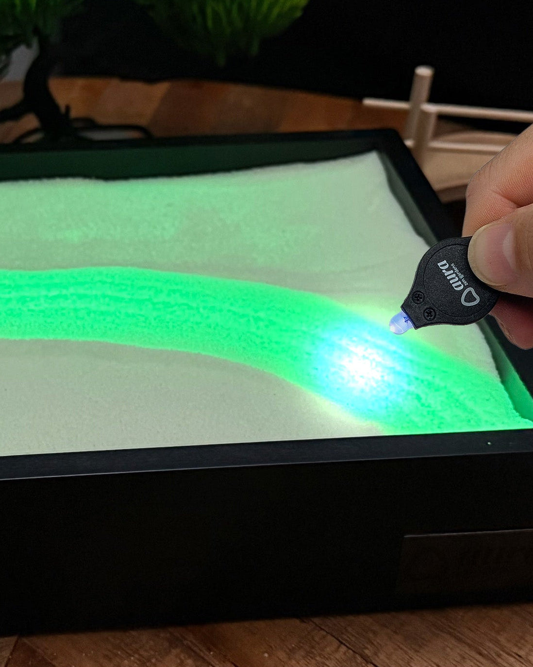 UV keychain light drawing a bright glowing line in Aura Glow Sand