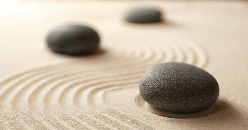 Smooth black stones resting in raked sand